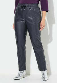 Mörkgrå konstläderbyxor med elastisk midja och dragsko, avsmalnande ben och sid sömmar för extra detalj, ihop med silverfärgade ankelstövlar.