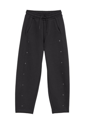 Pantalon de survêtement noir avec taille élastique et cordon, poches latérales et petits ornements en forme d’étoile argentée le long des coutures extérieures.