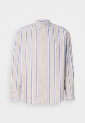 Napapaita, joka on valmistettu pehmeästä puuvillakankaasta, ja jossa on pystysuorat vaaleanbeige ja vaaleansininen raidat, pitkät hihat ja yksi rintatasku.