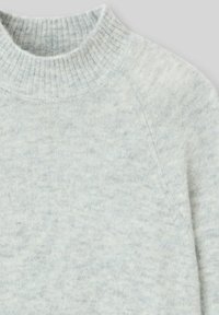 Pull en maille gris clair avec col montant à côtes, texture douce et finition confortable, présentant une apparence légèrement chinée.
