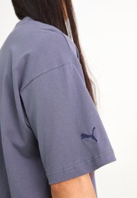 Camiseta de algodón gris con manga corta, con un logotipo de Puma bordado en color marino en la manga izquierda y un corte relajado.