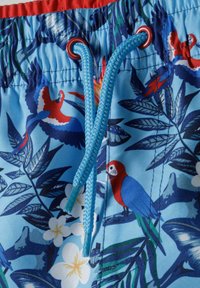 Pantaloni de baie albaștri cu un design tropical, având papagali roșii și albaștri, frunze verzi și flori albe. Curea elastică în talie cu șnur albastru.