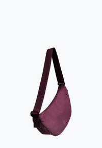 Slingtasche in tiefem Burgundy, aus glattem Stoff. Verfügt über einen breiten Riemen und ein minimalistisches Design mit einem subtilen Logo auf der Vorderseite.