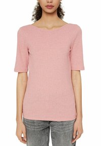 Top rosa a maniche corte a coste con scollatura ampia e silhouette aderente. La texture è morbida ed elastica, abbinata a jeans grigi.