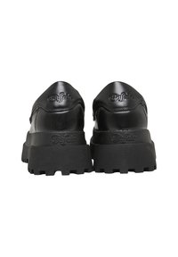 Les baskets noires présentent une tige brillante avec un bout arrondi et une semelle texturée. Le logo est embossé sur le talon. Design épais avec une semelle à relief prononcé.