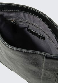 Borsa in pelle nera con superficie testurizzata, dotata di una tasca interna con zip e rivestimento in tessuto liscio.