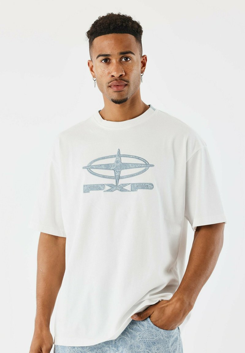 Camiseta blanca de manga corta con un logotipo gráfico azul que presenta una forma ovalada y el texto "PXP". Textura de algodón suave, corte regular.