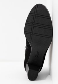 Sola di scarpa in suede nero con motivo di grip testurizzato e un leggero tacco. Presenta un'etichetta del marchio e la marcatura della taglia.