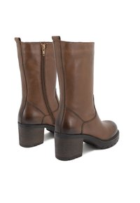 Stivali ankle in pelle marrone con finitura liscia, zip laterale e tacco a blocco. Presentano cuciture a sezioni e suola in gomma testurizzata.