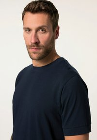 Námorně modré bavlněné tričko s kulatým výstřihem, krátkými rukávy a hladkým povrchem. Jednoduchý design bez viditelných vzorů nebo log.