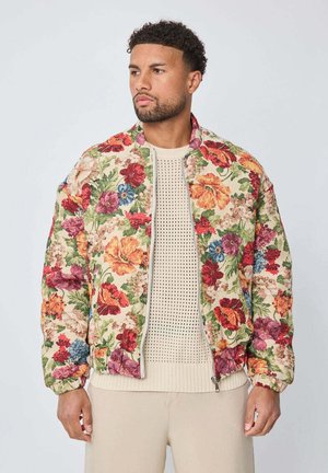 Veste bomber florale avec un fond beige et des fleurs colorées en rouge, rose et bleu. Tissu doux et rembourré avec des poignets côtelés.