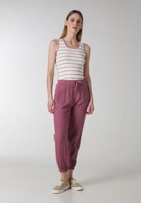 Lettet, stribet tanktop i hvid med lyserøde striber, parret med løstsiddende, dyb pink linnedbukser med elastisk talje og manchetter.