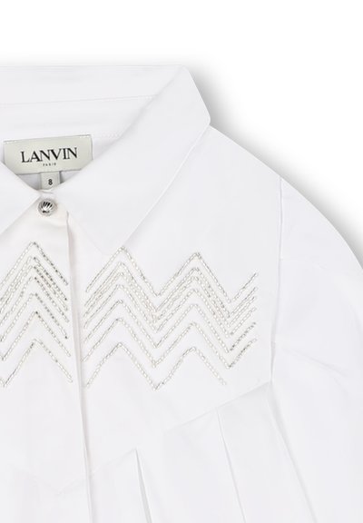 White shirt with a structured collar, featuring silver zigzag embroidery on the chest and vertical pleats along the front.