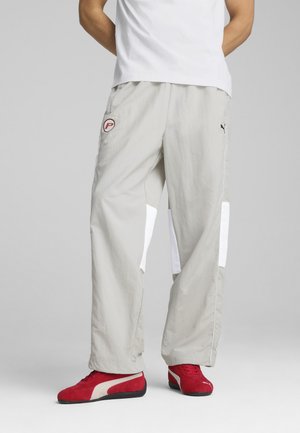 Light gray cargo pants with side white panels, featuring a round red logo and elastic waistband, paired with red athletic shoes.