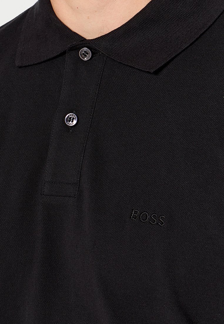 Polo noir en coton avec un col classique. Comprend trois boutons et un logo "BOSS" en relief sur le côté gauche.