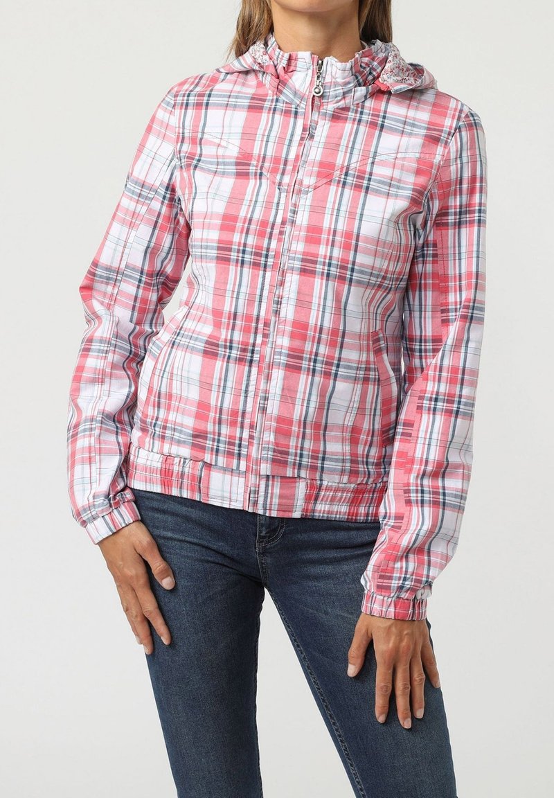 Chaqueta a cuadros en rosa, blanco y azul marino con cierre de cremallera y puños elásticos. Presenta una capucha fruncida y una textura de tela suave.