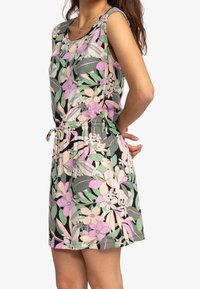 Blumenkleid mit schwarzem Grund und pinken, grünen und weißen Mustern, ärmelloses Design und taillierter Schnitt mit Kordelzug.