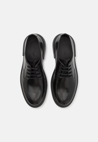 Black leather dress shoes with a smooth texture, lace-up design, rounded toe, and flat rubber sole. Logo embossed on the insole.