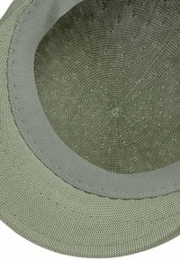 Cappello verde tessuto a forma rotonda, con una corona testurizzata e una visiera ampia e liscia. Dettagli delle cuciture e colore uniforme in tutto il cappello.