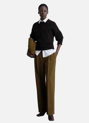 Pull en maille marron, chemise blanche à col, pantalon large vert olive, portant une pochette ocre. Texture lisse, coupe décontractée.