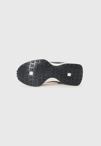 Semelle de chaussure en caoutchouc noir avec une surface texturée et des motifs rectangulaires, présentant une accentuation blanche sur le côté. Forme incurvée, conception durable.