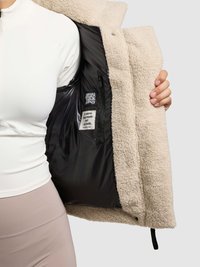 Giacca in pile color crema con esterno morbido e interno foderato nero, caratterizzata da un'etichetta e un'orlo regolabile.