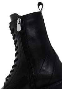 Stivale alla caviglia in pelle nera con zip laterale, lacci frontali e punta rinforzata. Texture liscia con dettagli di cucitura lungo le cuciture.