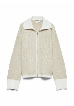 Beige og hvid strikket zip-sweater med høj krave og ribbede manchetter, præsenteret på en hvid baggrund.