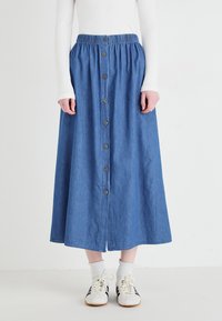 Gonna midi in denim con vita elastica e bottoni sul davanti. Presenta un colore azzurro chiaro, texture liscia e silhouette svasata.