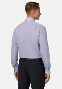 Svijetloplava i bijela prugasta košulja sa raširenim ovratnikom i dugim rukavima. Pruža dugmad na manžetama i prilagođeni kroj, prikazana s leđa.