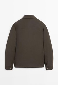 Mörkgrön, lättviktsjacka med långa ärmar, uppvikbar krage, knäppta manschetter och sömdetaljer vid axlarna.