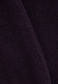 Ciemnofioletowa tkanina o miękkiej, teksturowanej powierzchni. Materiał wydaje się puszysty z delikatnym połyskiem, ukazując subtelne różnice w kolorze.