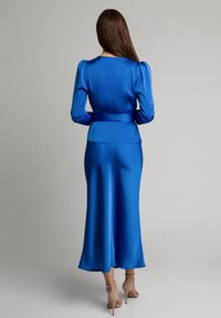 Niebieska sukienka z satyny z długimi bufkami, dopasowaną górą i zwiewnym dołem. Gładka faktura z paskiem w talii i subtelnym blaskiem.