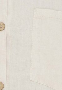 Hvid linnedskjorte med naturlige træknapper og en brystlomme, der har et struktureret stof med et subtilt, vævet udseende.