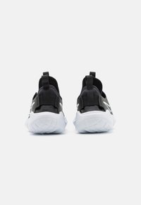 Zapatos deportivos negros con suelas blancas, parte superior de tela y tiradores en el talón. Sin patrones ni logotipos visibles en la vista trasera.