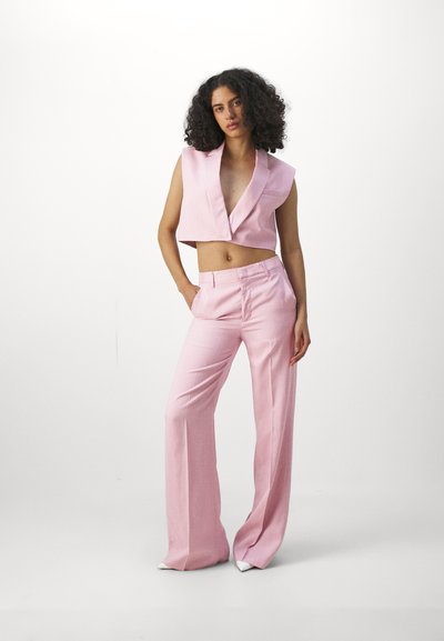 Ensemble deux pièces rose comprenant un blazer sans manches court avec un col cranté et un pantalon large taille haute. Texture de tissu lisse.