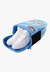 Lys blå skotui med svarte detaljer, glidelås lukking, med hvite høy-topp sneakers inni og teksten "JORDAN 23" på toppen.