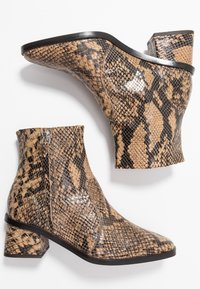 Botines de mujer con patrón de serpiente en tonos marrón y negro, tacones cuadrados y cremalleras laterales, mostrados desde vistas lateral e inferior.