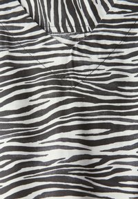 Tessuto a stampa zebra bianco e nero con design a V, caratterizzato da larghezze di strisce variabili e una texture liscia. Adatto per abbigliamento.