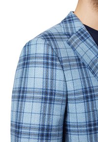 Niebieski blezer w kratę z teksturowanej tkaniny o jasnoniebieskiej bazie, akcentowany ciemniejszymi niebieskimi i czarnymi liniami, ze zbudowaną konstrukcją kołnierza.