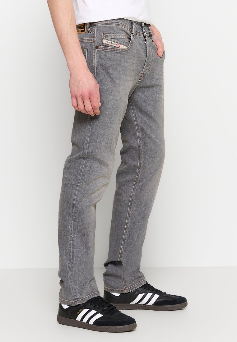 Grijze denim jeans met een rechte pasvorm, voorzien van een klassieke vijf-pocketontwerp en subtiele beschadigingen. Gemaakt in combinatie met zwarte sneakers.
