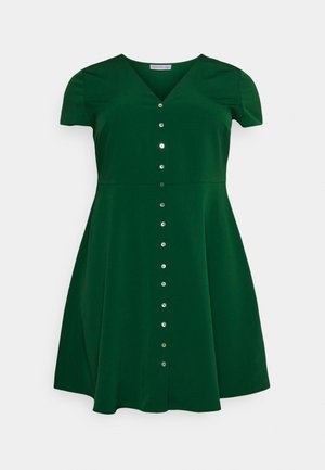 Donkergroene jurk met korte mouwen, V-hals, getailleerde taille, uitlopende rok en een rij zilveren knopen van boven tot onder.