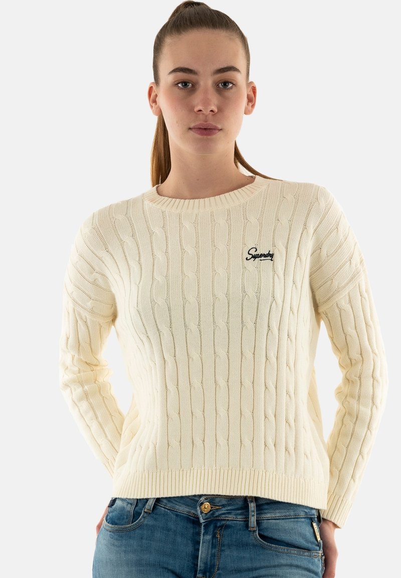 Jersey de punto trenzado color crema con cuello redondo y puños acanalados. Presenta un logo bordado en el lado izquierdo del pecho.