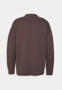Brauner Strickpullover mit geripptem Rundhalsausschnitt und hochgeschlagenen Ärmeln. Der Stoff wirkt weich mit einer strukturierten Oberfläche und entspannter Silhouette.