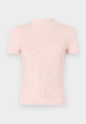 Haut rose clair à manches courtes avec un col haut, présentant un motif géométrique semblable à de la dentelle sur le devant et un tissu lisse sur les manches.