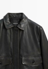 Schwarze Lederjacke mit glatter Textur, Knopfverschluss und spitzem Kragen. Verfügt über zwei Fronttaschen mit Klappenverschlüssen.