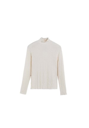 Top de manga larga color crema con una tela texturada y arrugada, que presenta un cuello simulando volantes y un corte relajado.