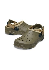 Zuecos verde oliva con un suave forro beige, que cuentan con orificios de ventilación y correas traseras ajustables. Suela de goma texturada para un mejor agarre.