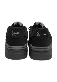 Sorte sneakers med overdel i ruskind, polstret krave og grå accenter. Har en tekstureret sål og signaturlogo på hælen.