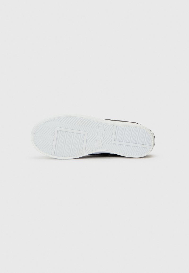 Sneaker nera con suola in gomma bianca, caratterizzata da un battistrada a motivi per una buona aderenza e una parte superiore liscia. Design semplice con dettagli minimi.